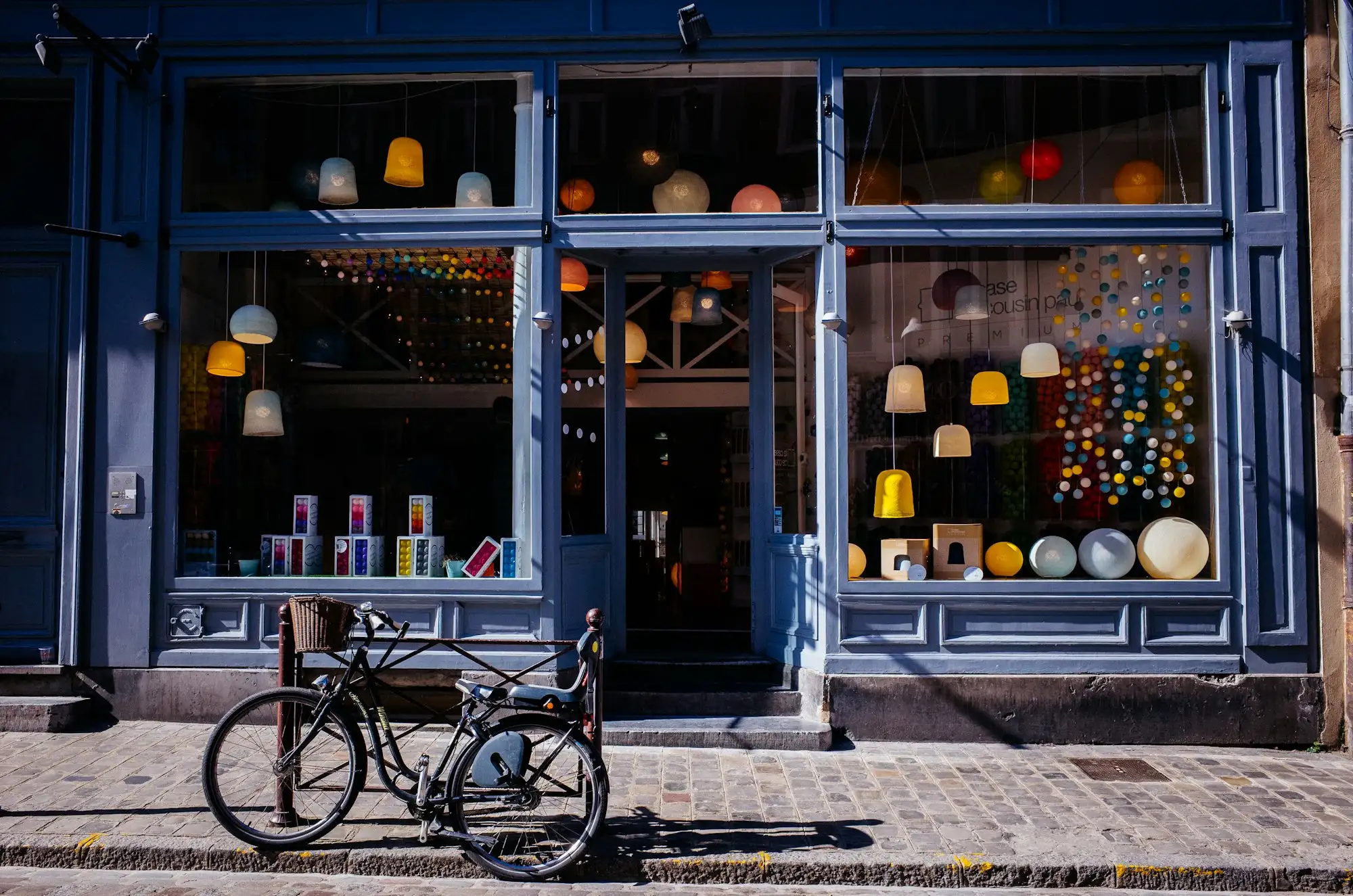 A blue-painted shopfront glowing at dusk with a bicycle leaning by the window